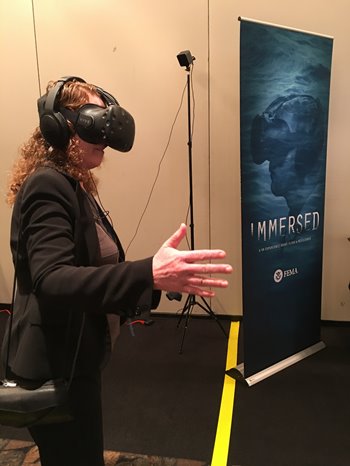 Image: Kelly Cobeen, a structural engineer and associate principal with Wiss, Janney, Elstner Associates Inc., tries “Immersed,” a virtual-reality experience on floods from the Federal Emergency Management Agency, at CEA’s second annual research forum in Sacramento.  Photo credit: California Earthquake Authority.