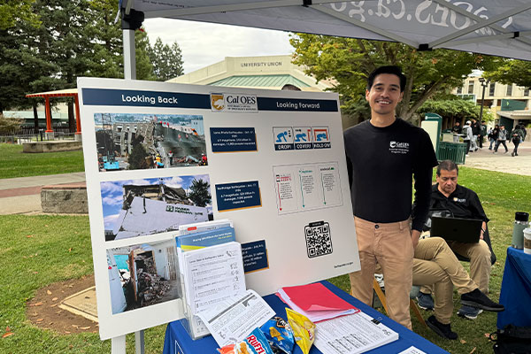 Image: Raul, an intern with Cal OES, next to pictures of major earthquakes in CA.