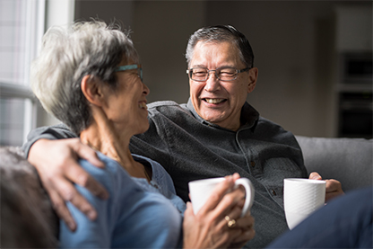 Image: Couple sitting on couch drinking coffee