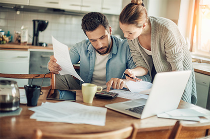 Image: Couple in a kitchen looking over documents on a table with a calculator