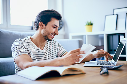 Image: Man at a table with documents and a laptop smiling